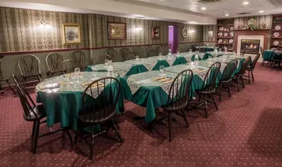 a long table in a room with green tables and chairs at The Globe Inn in East Greenville
