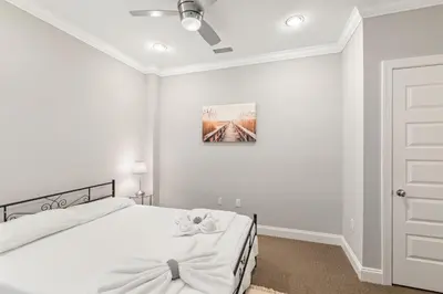 a white bedroom with a bed and a painting on the wall at Glam Flat with View, Pool, Deck in Philadelphia