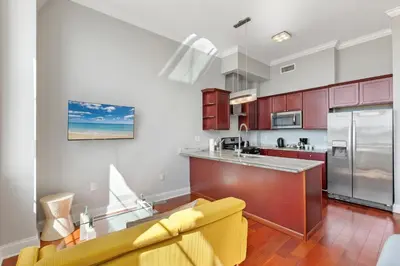 a kitchen with red cabinets and a yellow couch at Glam Flat with View, Pool, Deck in Philadelphia