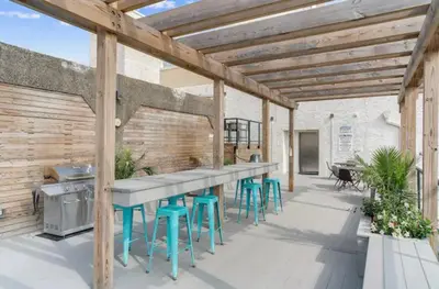 a patio with a bar with stools and a grill at Glam Flat with View, Pool, Deck in Philadelphia