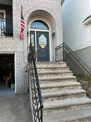 a set of stairs leading to a blue door with a flag at Comfort Apartment Near Newark Airport in Newark