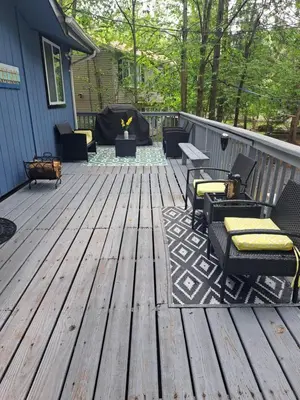 a deck with chairs and tables on a house at Fun Home in Pocono with Gameroom-Firpit-BBQ Grill-TV and AC in all rooms in Tobyhanna