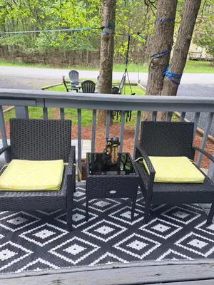 two chairs with yellow cushions sitting on a porch at Fun Home in Pocono with Gameroom-Firpit-BBQ Grill-TV and AC in all rooms in Tobyhanna