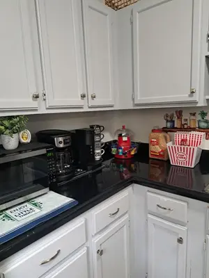 a kitchen with white cabinets and black counter tops at Fun Home in Pocono with Gameroom-Firpit-BBQ Grill-TV and AC in all rooms in Tobyhanna
