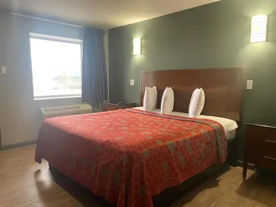 a hotel room with a bed with a red comforter at Wilkes-Barre lodge in Wilkes-Barre