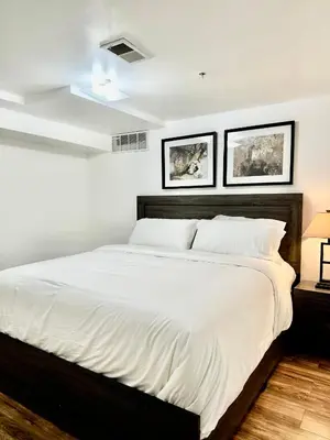 a bedroom with a large white bed with two pictures on the wall at Cozy Evergreen Apartment by Newark Airport in Newark