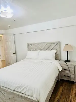 a white bedroom with a large bed and a lamp at Cozy Evergreen Apartment by Newark Airport in Newark