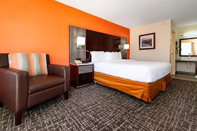 a hotel room with a bed and a chair at New Hope Inn & Suites in New Hope