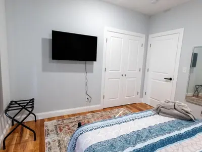a bedroom with a bed and a flat screen tv on the wall at 4 New Apts - 3 Bed Apt 1st Floor & 3 Bed Apt 2nd Floor - 1 Bed Studio Apt Ground Floor & 1 Bed Studio Apt Ground Floor near Penn Station EWR Airport Beth Israel Hospital Manhattan NYC in East Orange