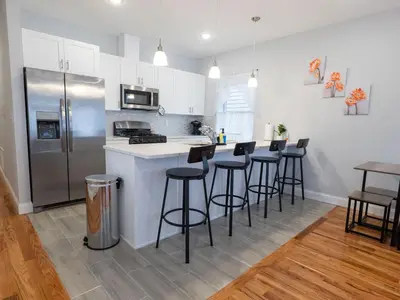 a kitchen with a stainless steel refrigerator and bar stools at 4 New Apts - 3 Bed Apt 1st Floor & 3 Bed Apt 2nd Floor - 1 Bed Studio Apt Ground Floor & 1 Bed Studio Apt Ground Floor near Penn Station EWR Airport Beth Israel Hospital Manhattan NYC in East Orange