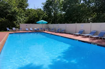 a large swimming pool with chairs and an umbrella at Comfort 2br2ba Monthly Discount in Elkins Park