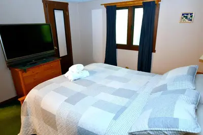 a bedroom with a blue and white bed and a tv at Ski-In Ski-Out Camelback Village Townhouse - 100 YDS From The Mountain in Crescent Lake