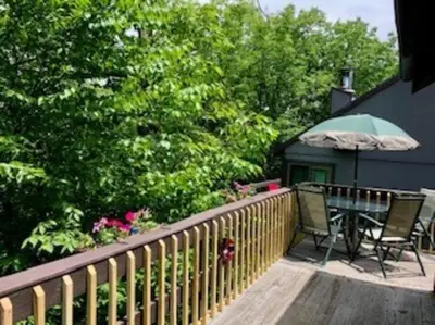 a wooden deck with a table and an umbrella at Ski-In Ski-Out Camelback Village Townhouse - 100 YDS From The Mountain in Crescent Lake