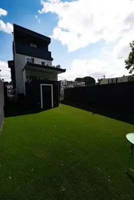 a building with a green yard with a building at 1BR Apt In Darby 18Min To Lincoln Financial Field in Darby
