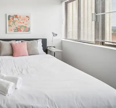 a white bedroom with a large white bed with pink pillows at PP 1301 Modern Corporate 2br, pool, Gym in Harrisburg