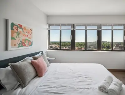 a white bedroom with windows and a bed with pillows at PP 1301 Modern Corporate 2br, pool, Gym in Harrisburg