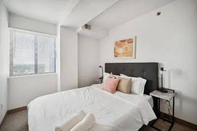 a white bedroom with a large bed with pink pillows at PP 1802 Modern Corporate 2br, pool, Gym in Harrisburg