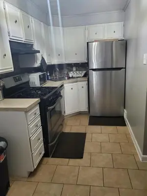 a kitchen with white cabinets and a stainless steel refrigerator at Tranquility Room by the Airport -Shared space in Darby