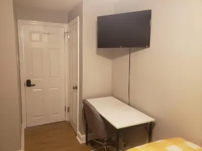 a room with a desk with a television on the wall at Tranquility Room by the Airport -Shared space in Darby