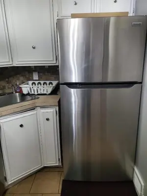 a stainless steel refrigerator in a kitchen with white cabinets at Tranquility Room by the Airport -Shared space in Darby