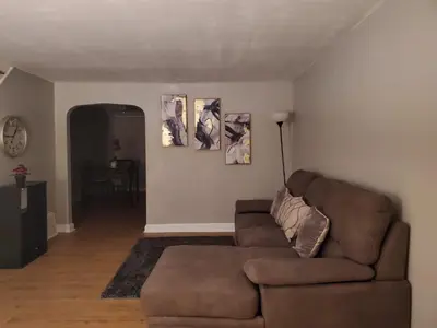 a living room with a brown couch and pictures on the wall at Tranquility Room by the Airport -Shared space in Darby