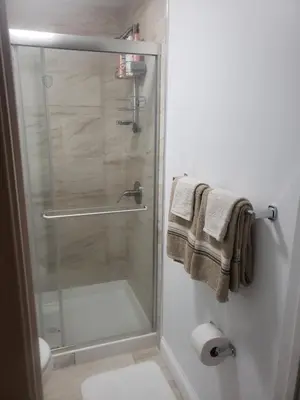 a bathroom with a glass shower stall with towels at Harmony Room with private bathroom by the Airport in Darby