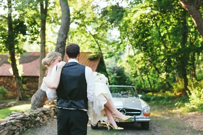 a bride and groom standing in front of a car at Inn at Glencairn in Princeton