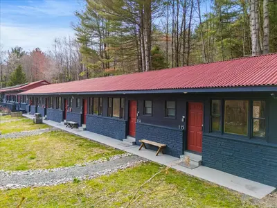 a row of blue buildings with red doors and benches at Green Acres Retreat in Hancock