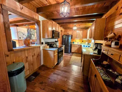 a large kitchen with wooden cabinets and a refrigerator at Secluded Mountain Lodge Near Williamsport with a Fireplace, Deck, and Pet-Friendly in Linden