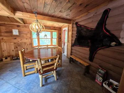 a dining room with a table in a log cabin at Secluded Mountain Lodge Near Williamsport with a Fireplace, Deck, and Pet-Friendly in Linden