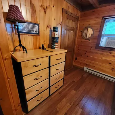 a bedroom with a dresser and a lamp in a cabin at Secluded Mountain Lodge Near Williamsport with a Fireplace, Deck, and Pet-Friendly in Linden
