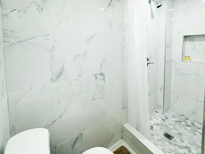 a white bathroom with a shower and a toilet at Lux Designer Home with Gaming Rm in Jersey City