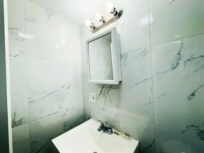 a white bathroom with a sink and a mirror at Lux Designer Home with Gaming Rm in Jersey City