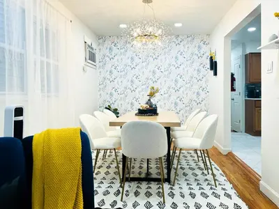 a dining room with a table and white chairs at Lux Designer Home with Gaming Rm in Jersey City