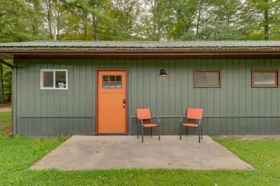 a green house with two chairs and a orange door at Community Perks Elk Creek Escape - Deluxe Cabin C in Hillsgrove