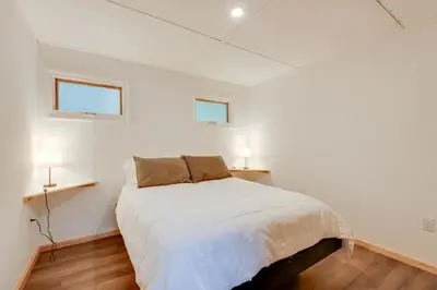 a white bedroom with a bed and two windows at Shared Perks Deluxe Cabin B at Elk Creek Escape! in Hillsgrove