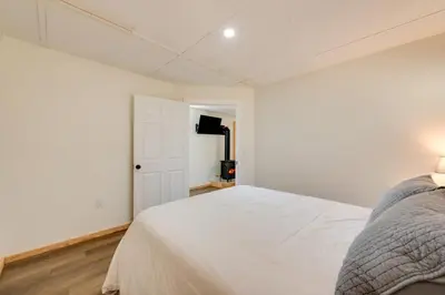 a white bedroom with a bed and a door at Hillsgrove Deluxe Cabin E Close to Hiking in Hillsgrove