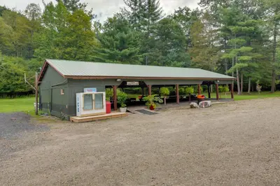a large green building with a porch on a field at Hillsgrove Deluxe Cabin E Close to Hiking in Hillsgrove