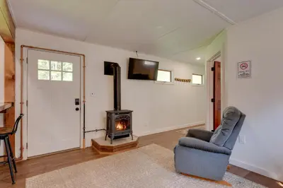 a living room with a wood stove and a chair at 9 Mi to Worlds End State Park Deluxe Cabin H in Hillsgrove