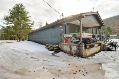 a building with snow on the ground in front of it at Deluxe Cabin G 9 Mi to Worlds End State Park! in Hillsgrove
