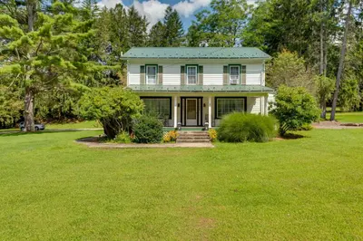 a white house with a green roof on a yard at The Big House at Elk Creek Escape with Game Room in Hillsgrove