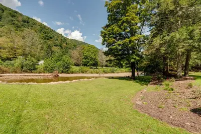 a grassy field next to a river with trees at The Big House at Elk Creek Escape with Game Room in Hillsgrove