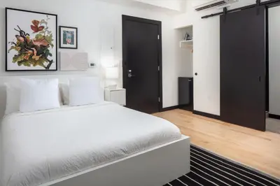 a bedroom with a white bed and a black door at Kasa The Niche University City Philadelphia in Philadelphia