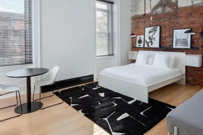 a bedroom with a white bed and a brick wall at Kasa The Niche University City Philadelphia in Philadelphia