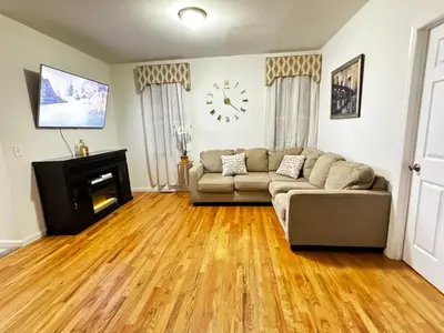 a living room with a couch and a clock on the wall at Private 1st floor Apartment - Only 5 min Away from Newark Airport and 30 min to NYC in Elizabeth