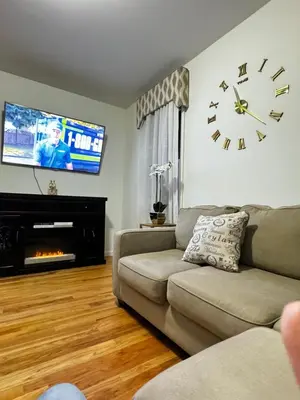 a living room with a couch and a clock on the wall at Private 1st floor Apartment - Only 5 min Away from Newark Airport and 30 min to NYC in Elizabeth