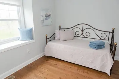 a bedroom with a bed with blue pillows and a window at Spacious Modern Home in West Freehold in Stonehurst West