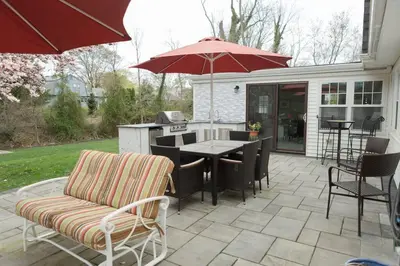 a patio with a table and chairs and an umbrella at Spacious Modern Home in West Freehold in Stonehurst West
