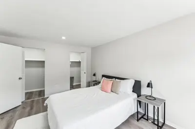 a white bedroom with a large bed and a table at Pine Brook 1111 I State of the art 15 Bd Apt in Newark