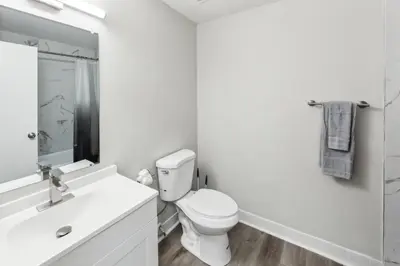 a white bathroom with a toilet and a sink at Pine Brook 1111 I State of the art 15 Bd Apt in Newark